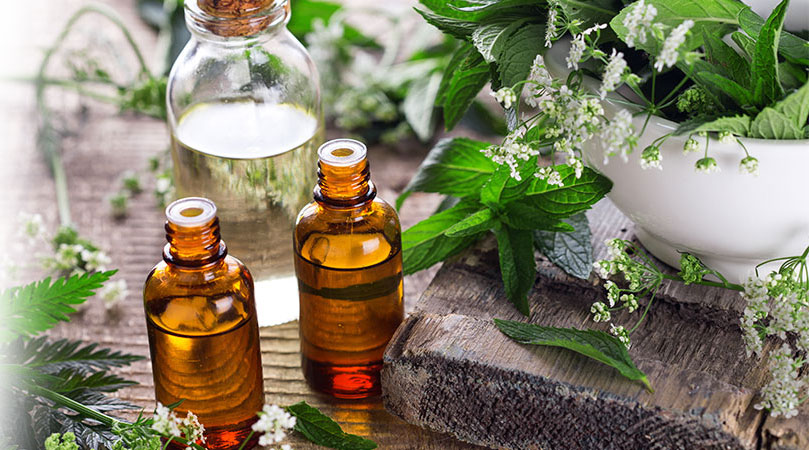 A collection of essential oils arranged for skin care, featuring various bottles and natural ingredients.